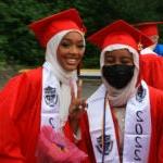 Two graduates smile for a photo in cap and gown.